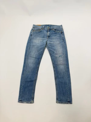 Dondup jeans - Säljer ett par ljusblå jeans med raka ben och slitningar på framsidan. Jeansen har klassisk femficksdesign och subtila detaljer på bakfickorna. Tillverkade i denim med en snygg tvättad look.