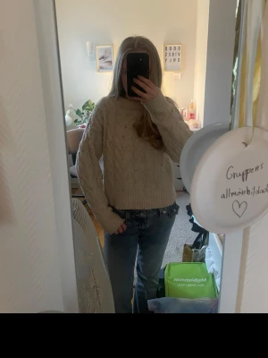 Beige kabelstickad tröja - Mysig beige kabelstickad tröja med rund hals och långa ärmar. Tröjan har ett klassiskt flätmönster och ribbade muddar vid ärmslut och nederkant. Perfekt för lager-på-lager och passar till jeans eller kjol. Från Gina Tricot. Lite stor i storleken