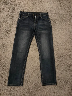 Mörkblå jeans från Armani - Snygga mörkblå jeans från Armani. Raka ben och tydliga kontrastsömmar. Bakfickorna har Armani-logga. Perfekta för en stilren och trendig look.