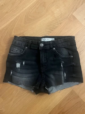 Svarta jeansshorts från Amisu - Snygga svarta jeansshorts från Amisu med slitna detaljer och rå kant nertill. Klassisk femficksmodell med knapp och dragkedja framtill. Perfekta för dig som gillar en edgy och trendig stil.💕💕