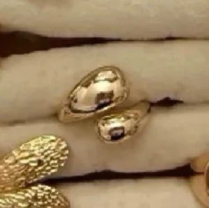 4 för 3 - Snygg guldfärgad ring med två droppformade, blanka detaljer. Ringen har en modern och chunky design som verkligen sticker ut. Perfekt för dig som gillar att bära unika accessoarer och vill addera lite edge till din stil.