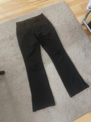 Svarta kostymbyxor med bootcut - Säljer ett par svarta lågmidjade kostymbyxor med bootcut-modell storlek S (36) köpta för 499kr från BikBok . Hällor för skärp och två fickor bak. Materialet är slätt och ger en stilren look. Perfekta till en snygg outfit när du vill känna dig extra uppklädd! 