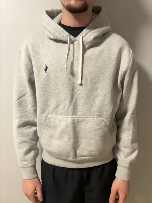 Ljusgrå hoodie från Polo Ralph Lauren - Snygg ljusgrå hoodie från Polo Ralph Lauren med klassisk broderad logga på bröstet. Hoodien har huva med dragsko, magficka och ribbade muddar. Perfekt för en chill och stilren look. Mjuk bomullsblandning som känns skön mot huden. Hör av er vid frågor eller funderingar ‼️