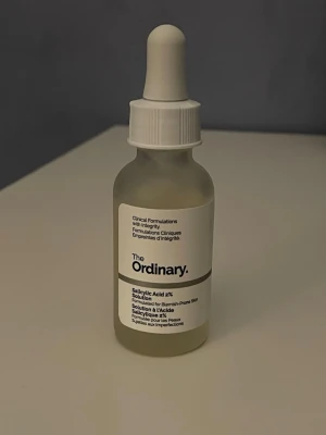 The Ordinary Salicylic Acid 2% Solution - En genomskinlig glasflaska med pipett från The Ordinary, innehållande Salicylic Acid 2% Solution. Perfekt för dig som vill behandla orenheter och få en klarare hud. Enkel att applicera tack vare pipetten och stilren design i vitt och svart.