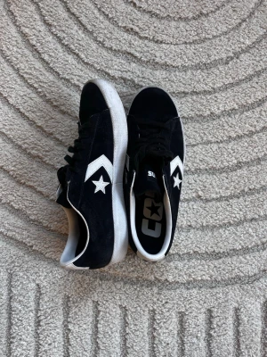 Svarta Converse - Snygga svarta Converse One Star sneakers i mocka med vit sula och vita detaljer. Klassisk stjärnlogga på sidan och svarta snören. 