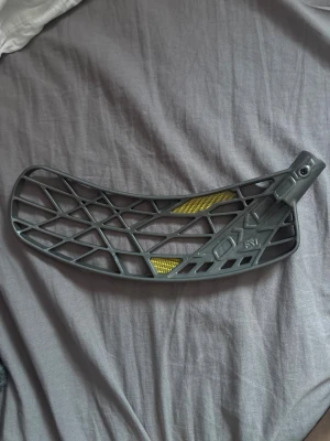 Grå innebandyblad från Oxdog - Säljer ett grått innebandyblad från Oxdog med coolt rutnät och detaljer i gult. Bladet är tillverkat i plast och har en modern, lätt design som passar perfekt för snabba spelare. Perfekt för dig som vill uppgradera din klubba med stil. Fsl blad 