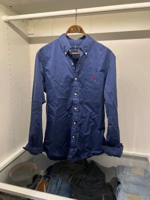 Ralph Lauren skjorta - En riktigt fin skjorta ifrån Ralph Lauren! Skjortan är i storlek M slim fit och av ett featherweight material som gör den lätt att bära! Den har en liten skavank i tyget som kan ses på en av ärmarna på sista bilden, men ingent som märks om man inte vet om den enligt mig! Annars är skjortan i ett utmärkt skick! Om du är i behov av bilder är det bara att fråga efter det, samt bilder på mig i den! Nypris: ca 1600kr. Fraktar senast dagen efter beställning!