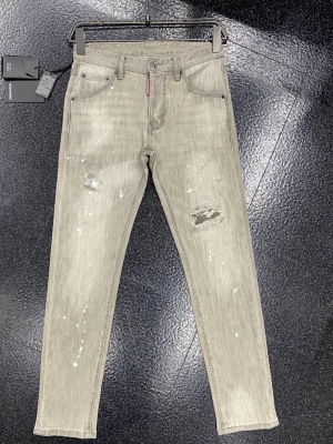Gråa slitna jeans från Dsquared2 - Säljer ett par slitna  från Dsquared2 med slitningar och vita färgstänk för en cool, trendig look. Fråga för flera bilder!! pris diskuteras
