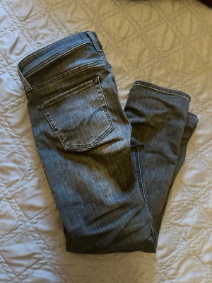 Mörkblå jeans från Jack & Jones - Snygga svarta jeans från Jack & Jones med klassisk femficksdesign och diskreta sömmar på bakfickorna. Jeansen har en rak passform och är tillverkade i stretchigt denim för extra komfort. Perfekta för en stilren och avslappnad look. Dom är helt nya har använts 3 gånger och jag säljer dom för att dom passade inte