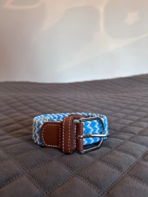 Ljusblå vitt flätat bälte - Tja det är helt nytt från bältgallerian i storlek 105cm långt och 3,5cm brett. Det är gjort i ett elastiskt material och man kan anpassa längden vart man än vill. Om du inte gillar den här färgen finns flera andra att välja mellan. Desto mer du köper desto billigare blir det. Säljer också armband.