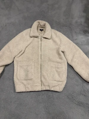 Teddyjacka - Mysig beige teddyjacka med två stora framfickor och dragkedja framtill. Jackan är i storlek 40 men passar bra som en S 🥰 Den har använts och tvättats men har inga defekter! 