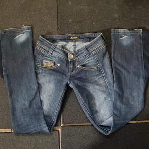 Blå vintage bootcut jeans  - Snygga blå jeans från Killah med gul kontrastsöm och diskret slitning. Jeansen har låg midja och är i storlek som passar mig som ofta klär i xs-s, tillverkade i mjukt denimtyg. Perfekta för dig som gillar en cool och avslappnad stil.