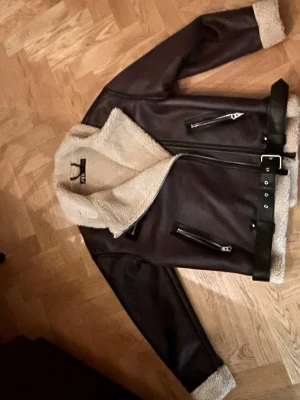 Brun teddyjacka från Zara med bälte - Säljer en brun teddyjacka från Zara med krämfärgat foder och detaljer. Jackan har bred krage, dragkedjor, bälte i midjan och muddar i samma teddy-material. Den är använd fåtal gånger och har inga skador!! Den är lite oversize. Perfekt för dig som vill ha en trendig och varm jacka med stil!!🩷