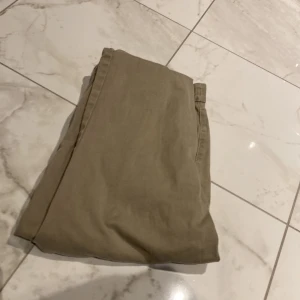 Beige bomullsshorts från NEXT - Snygga beige shorts från NEXT i mjuk bomull med klassisk passform. De har knapp och dragkedja fram, bälteshällor och fickor både fram och bak. Perfekta för chill dagar och sommarhäng. Passar dig som gillar enkel och clean stil.