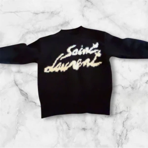 Svart stickad Saint Laurent tröja - Svart stickad tröja från Saint Laurent med stort vitt logotryck på bröstet. Tröjan har rund hals och långa ärmar, perfekt för dig som gillar statement-plagg och exklusiv design. Materialet är mjukt och håller värmen, med en loose passform som ger en chill vibe.