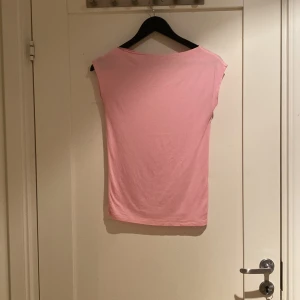 Ljusrosa ärmlös topp i bomull - Säljer en ljusrosa topp från 157 i storlek XS. Toppen är enkel och stilren med rund hals och ärmlös design. Tillverkad i mjuk bomull som känns skön mot huden. Perfekt för dig som gillar minimalistisk och fräsch stil.