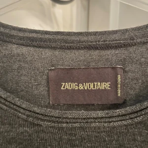 Mörkgrå merinoullströja Zadig & Voltaire - Snygg mörkgrå långärmad tröja från Zadig & Voltaire i 100% mjuk merinoull🍁 Enkel design med rund halsringning och diskret döskallemönster på ryggen.  Nypris över 2000 kr! Mitt pris - 289 kr💫 Mycket bra skick, som ny