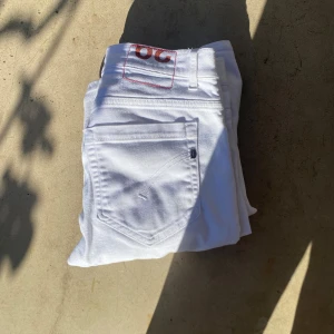 Vita jeans från Dondup - Snygga vita Dondup  jeans med klassisk femficksdesign och röd logotyp på bakfickan. Jeansen har rak passform och är tillverkade i slitstarkt bomullsmaterial. Perfekta för dig som vill sticka ut med en fräsch och clean look. Dessutom helt nya