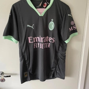 AC Milan fotbollströja - AC Milan fotbollströja från Puma i svart med ljusgröna detaljer vid krage och armslut. Tröjan passar till allt och pr riktigt fet 