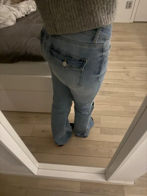 Ljusblå bootcut jeans med slitningar - Säljer ett par ljusblå bootcut jeans med snygga slitningar över knäna och klassiska fickor med lock och knapp. De är från Nelly och endast använda en gång. Säljer eftersom jag fick dom i present och kan inte lämna tillbaka. 