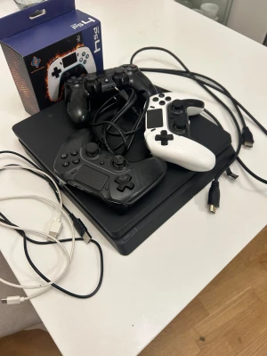 PlayStation 4 med 3 handkontroller - En helt fungerande playstation 4, använd i cirka 3 år men alla funktioner fungerar. Har 1 TB. Finns inga problem med den förutom att det kanske tar ett par försök för konsolen att scanna ett spel (skiva alltså).  Rengjord inifrån och gör knappt ljud. Fick en Playstation 5 och därför så behöver jag inte ps4 längre. Den originella ps4 kontrollen fungerar men inte helt, men de andra två kontrollerna av Deltaco gaming är båda köpta detta år och fungerar som nya. Kablarna till konsolen ingår, samt la