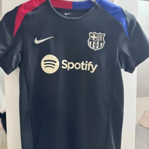 Svart FC Barcelona fotbollströja Nike XS - Säljer en svart FC Barcelona fotbollströja från Nike med Dri-FIT material. Tröjan är använd ett fåtal gånger och är i fint samt bra skick.