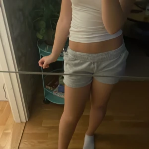 Grå mjuka shorts med snörning - Säljer ett par grå shorts med elastisk midja och snörning framtill. De är tillverkade i mjukt bomullsmaterial och har en loose passform som är skön att ha på sig. Perfekta för chill dagar eller träning. Färgen är ljusgrå och de har diskreta fickor på sidorna.