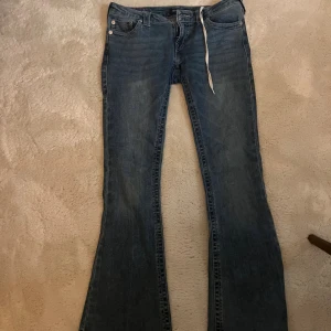 True Religion blå bootcut jeans - Lågmidjade jeans från true religion i storlek 28, storlek S/M. Dom är uppsprettade längst ner och har även satt i ett skosnöre i midjan men vill man inte ha de är de bara o dra ut så kommer de inte synas. Annars i väldigt bra skick och tvättas självklart innan dom skickas, skriv för måtten. Priset går absolut att diskutera