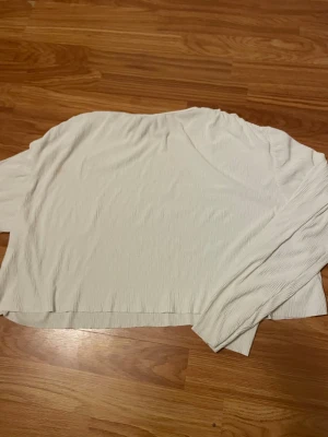 Vit långärmad topp från H&M - Vit långärmad topp från H&M i storlek S. Materialet är lätt och har en snygg ribbad struktur som ger lite extra känsla. Enkel och clean design med rund hals, perfekt att styla med jeans eller kjol. Fräsch och stilren för dig som gillar minimalistiskt.