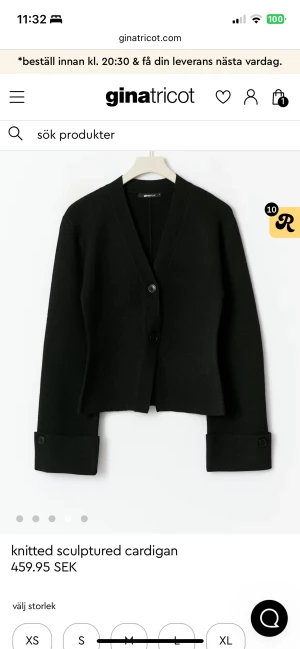 Svart kofta med knappar från Gina Tricot - Stilren svart kofta från Gina Tricot med v-ringad hals och två knappar framtill. Tröjan har långa ärmar med breda muddar och knappdetaljer. Den är stickad och har en skulpturerad, lite boxig passform som ger en cool vibe.