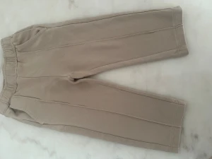 Beige mjukisbyxor med resårmidja - Säljer ett par beige mjukisbyxor med resår i midjan och raka ben. Byxorna har fickor fram och en enkel bakficka. Materialet är mjukt och skönt, perfekt för chill dagar. Snyggt minimalistiskt snitt och neutral färg som passar till allt.