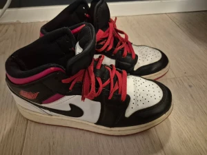 Nike Air Jordan 1 svart/vit/röd - Säljer ett par Nike Air Jordan 1 sneakers i svart, vitt och rött med röda skosnören och klassisk Jordan-logga.