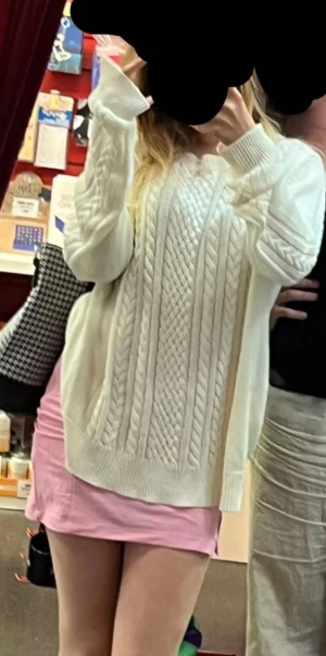 Vit stickad kabeltröja med lång ärm - Säljer en vit stickad tröja med snyggt kabelmönster framtill och på ärmarna. Tröjan har lång ärm, ribbade muddar och en loose passform som ger en chill vibe. Perfekt att slänga på sig när det är lite kyligt ute. (Dåligt ljus på senare bilder är vitare irl)