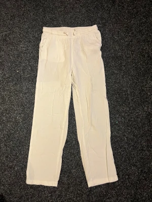 Vita linnebyxor med snörning - Snygga vita linnebyxor med rak passform och elastisk midja med snörning. Perfekta för chill dagar och har en clean look som funkar till sneakers eller sandaler. Materialet är linne som ger en skön och luftig känsla.