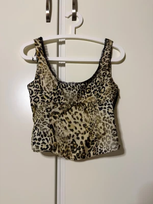 Leopardlinne från Zara - Säljer en snygg leopardmönstrad linnetopp från Zara i storlek XS, men passar även en S. Toppen har svarta spetsdetaljer längs urringningen och en liten rosett framtill. Materialet är glansigt och lätt, perfekt för att sticka ut och passar alla tillfällen. Stängs med dragkedja på sidan. Ny med prislapp kvar. Nypris 379kr🩷