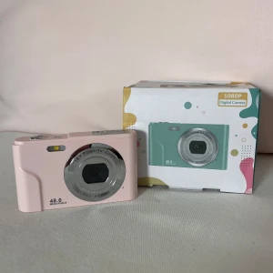 Digital kamera    - (Helt oanvänd) puder rosa digital camera, laddare & minneskort ingår. Super fint skick! Frakten ingår ej. Pris kan diskuteras. Bilderna visar en rosa digitalkamera med 48 megapixlar och 16x zoom. Kameran har en stor display på baksidan och flera knappar för enkel navigering. Perfekt för dig som vill ta snygga bilder till sociala medier eller dokumentera äventyr med vänner. Säljs med originalförpackning.