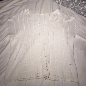 Vit stickad tröja från Lager 157 - Säljer en vit stickad tröja från Angelology i storlek M. Tröjan har ett snyggt hålmönster i vertikala ränder och v-ringad hals. Den är långärmad och har en mjuk, lite loose passform som är perfekt för chill dagar. 