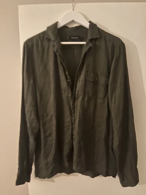 Linneskjorta från Riley - Olivgrön skjorta från Riley i 100% linne, perfekt för dig som gillar en chill och luftig stil. Skjortan har klassisk krage, knappstängning och en bröstficka med knapp. Långärmad och loose fit för extra komfort. Stl M Skick 9/10