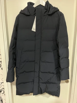 Navy dunjacka från Uniqlo XS - Säljer en navy (mörkblå) lång dunjacka från Uniqlo i storlek XS. Enkel och stilren design som funkar till allt. (HELT NY)