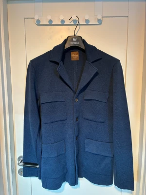 Blå overshirt från Stenströms, M - Snygg blå overshirt från Stenströms med fyra stora fickor framtill och klassisk krage. Jackan är stickad i ett mjukt material och har knäppning med knappar. Perfekt för dig som gillar stilren och avslappnad look.