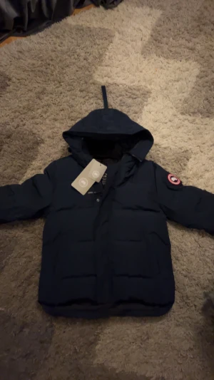 Mörkblå dunjacka från Canada Goose Macmillan - Säljer en mörkblå Canada Goose Macmillan i storlek L. Den är i bra skick och perfekt för vintern. Varm, stilren och redo för en ny ägare. Skickas snabbt eller kan hämtas efter överenskommelse.