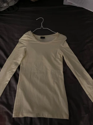 Ljusgul långärmad topp från Cubus - Säljer en enkel och stilren ljusgul långärmad topp från Cubus i storlek XS. Toppen har rund halsringning och är gjord i mjuk bomull, perfekt för att bygga lager eller bära som den är. Passformen är normal och materialet känns skönt mot huden.