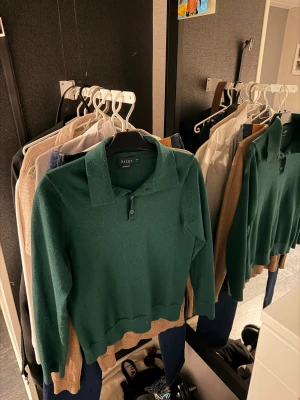 Grön merinoull pikétröja från ” Riley ” - Snygg mörkgrön pikétröja från Riley i mjuk merinoull. Tröjan har klassisk krage och två knappar framtill, perfekt för dig som gillar stilrena och bekväma plagg. Tröjan är i mycket bra skick! Storlek M men krympt i tvätten, passar XS! 