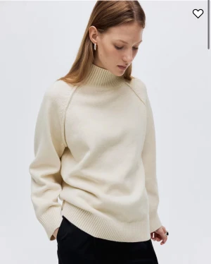 Beige stickad polotröja med ribbad krage - Säljer en beige stickad polotröja med hög ribbad krage och långa ärmar. Tröjan har en relaxed passform och breda ribbade muddar vid ärmslut och nederkant. Perfekt för lager-på-lager under kyliga dagar. Storlek M sitter som S/XS! Använd fåtal gånger💕