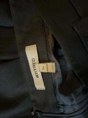 Svart kortkjol från Whyred, strl 34, med två fickor för fram - Snygg svart kjol från Whyred i storlek 34. Kjolen har en kort, utsvängd form med bred linning och markerade veck som ger extra volym. Stängs med dragkedja i sidan. Perfekt för dig som gillar stilrena och klassiska plagg med lite edge.Två fickor där fram