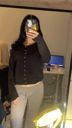 Mörk brun kofta med guldfärgade knappar - Mörk brun kofta med lång ärm och snygga guldfärgade knappar framtill. Modellen är lite croppad och har en klassisk, enkel design som passar till många olika stilar. Materialet känns mjukt och skönt mot huden, perfekt för dig som gillar stilrena plagg med en twist.