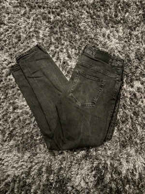 Svarta jeans från Revolution  - Snygga svarta jeans från Revolution i klassisk femficksmodell. Jeansen har en slim/rak passform och normal midja, med subtila fades för en cool look. Materialet är mjukt och slitstarkt denim som sitter skönt hela dagen.