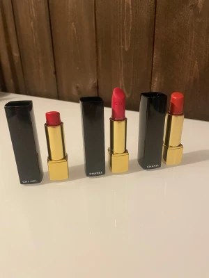 Chanel Rouge Allure läppstift - Tre Chanel Rouge Allure läppstift i färgerna: - 64 Enthusiast - 65 Insolente - 21 Exotic Använda och har några år på nacken. Kanske kan användas som dekoration. Alla tillsammans.