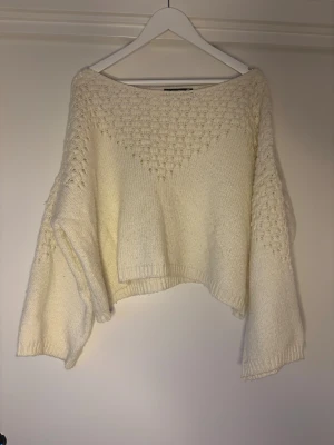 Vit stickad tröja från BikBok - Supermysig vit stickad tröja från BikBok i ullblandning. Tröjan har ett snyggt strukturmönster upptill och på ärmarna, samt en lite lös och boxig passform med långa ärmar. Perfekt för kyliga dagar och enkel att styla till jeans eller kjol.