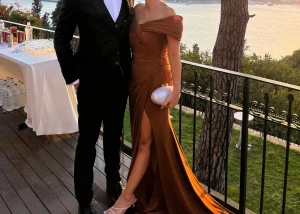 Brun långklänning med slits - Säljer en elegant brun långklänning med offshoulder och draperad överdel. Klänningen har en snygg slits framtill och markerad midja, vilket ger en riktigt lyxig känsla. Perfekt för bal eller festliga tillfällen. 